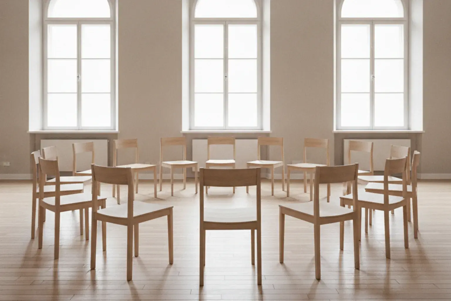 Ein leerer Stuhlkreis in einem Klassenraum mit heller Wand und Fenstern